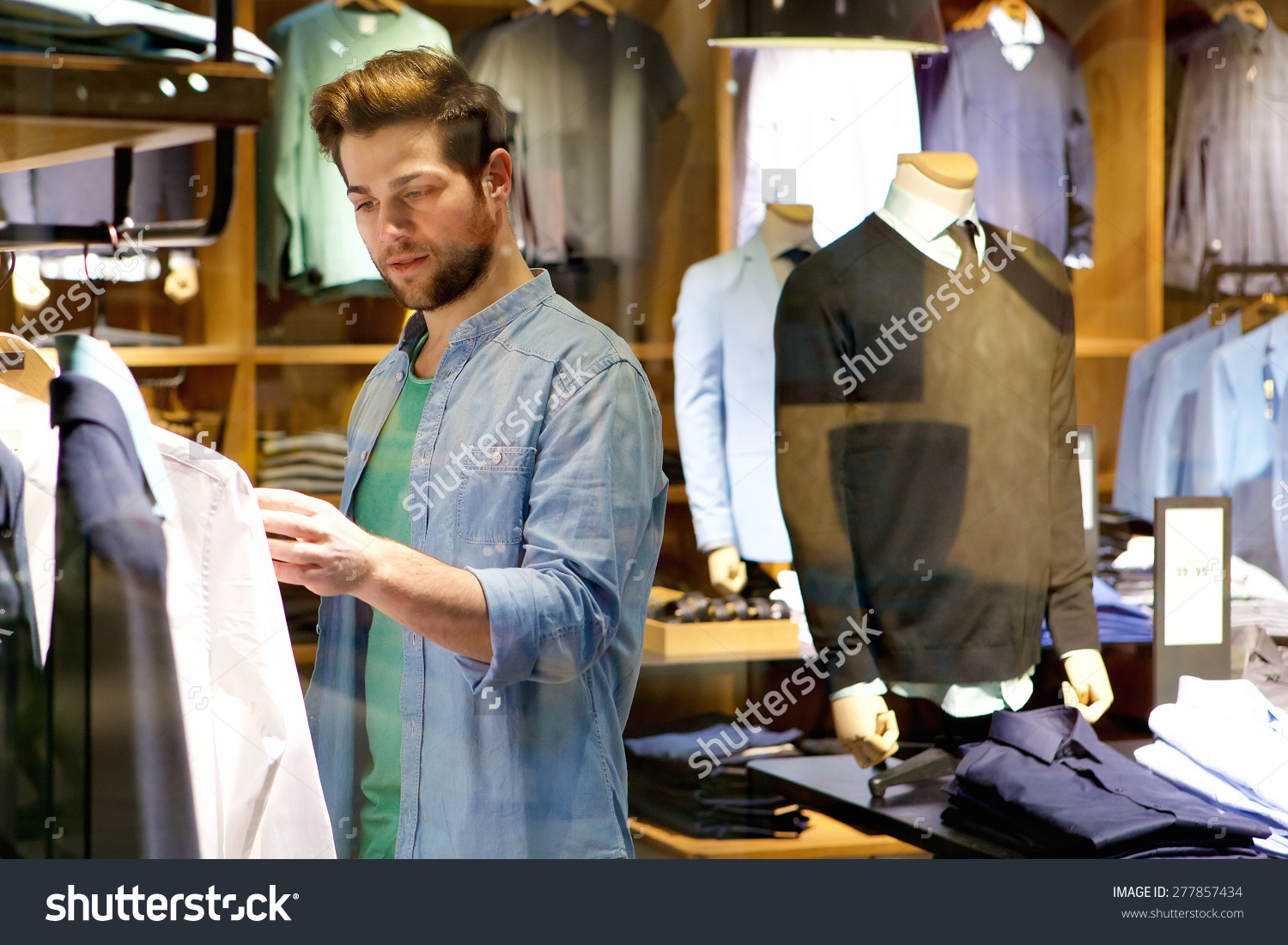 stock-photo-portrait-of-a-young-man-looking-at-clothes-to-buy-at-shop ...